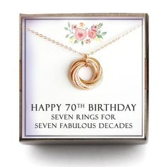 a birthday card with a gold necklace in the shape of a circle and flowers on it