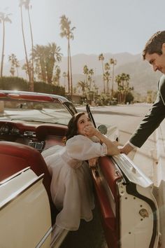 a bride and groom getting out of the back of a vintage convertible car with palm trees in the background