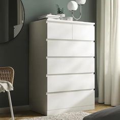 a white dresser sitting in a bedroom next to a window