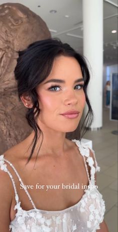 a woman in a white dress posing for a photo with her hair pulled back and eyes closed