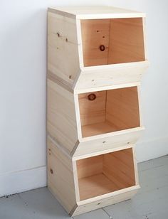 three wooden boxes stacked on top of each other in front of a white wall and floor