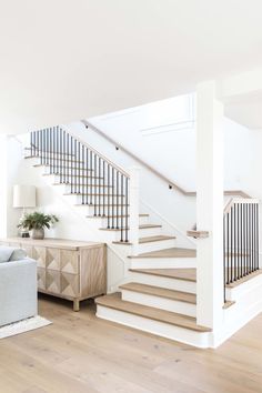 a living room filled with furniture and a stair case next to a white couch on top of a hard wood floor