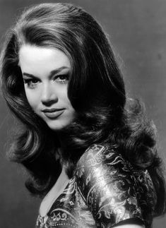 a black and white photo of a woman with long hair, wearing a patterned dress