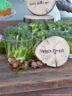 some broccoli and other vegetables are in small plastic cups on a table with the words veggie forest