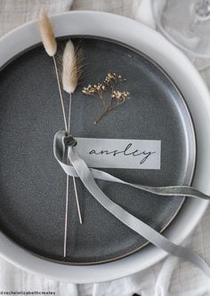 an empty plate with a name tag and some dried flowers on the side, tied to it