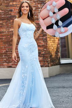 a woman in a blue dress holding up a diamond ring with her hand on the ground