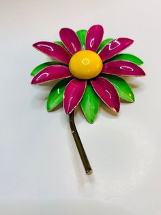 Large flower brooch with long brown stem with green and purple enamel paint petals with domed yellow enamel paint Center. Measurements are 2 1/2 inches around stem is 2 1/4 inches long. Good condition for its age. Green Flower-shaped Enamel Brooch Pin, Green Flower Shaped Enamel Pin Brooch, Green Flower Enamel Pin Brooch, Green Flower-shaped Brooch Pins, Green Flower Brooch Pins, Green Flower Shaped Brooch Pins, Purple Petals, Metal Flower, Enamel Paint