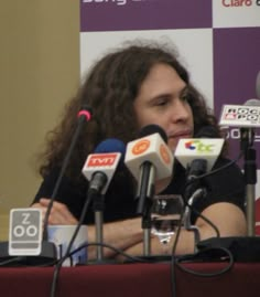 a man sitting at a table with microphones in front of him