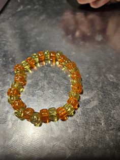 This orange and green beaded bracelet is fun for everyone! Great for parties, concerts and more! Yellow Beaded Bracelet For Party, Adjustable Yellow Beaded Bracelet For Parties, Casual Yellow Bracelets With Letter Beads, Party Bracelets With Colorful Beads In Yellow, Casual Adjustable Stretch Bracelet For Party, Casual Party Jewelry With Letter Beads, Casual Letter Beads Jewelry For Party, Green Stretch Bracelet With Colorful Beads For Party, Orange Beaded Bracelets For Party