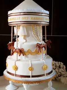 a three tiered white wedding cake with gold decorations on it's sides and the words camells get married