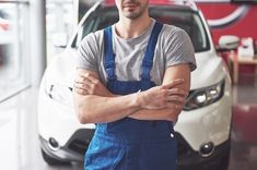 a man standing in front of a car with his arms crossed and looking at the camera