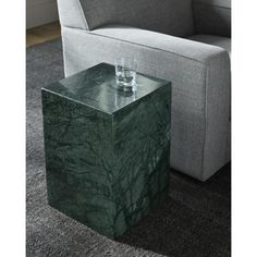 a green marble side table sitting on top of a carpeted floor next to a gray couch