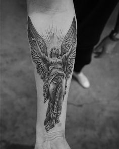 a person with a tattoo on their arm that has an image of the statue of jesus