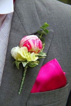 a boutonniere with pink and white flowers on the lapel of a man