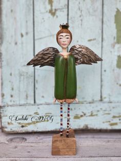 an angel figurine is standing in front of a wooden door with green paint