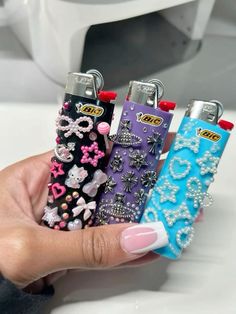 a person holding four lighters in their hand with bows and jewels on the sides