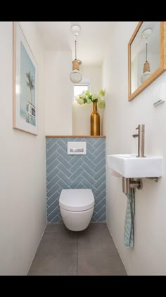 a white toilet sitting in a bathroom next to a sink under a mirror and framed pictures