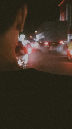 a woman looking out the window at traffic on a busy city street in the dark