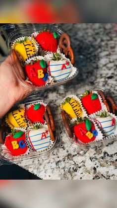 two plastic containers filled with decorated cookies on top of a marble counter topped with pretzels