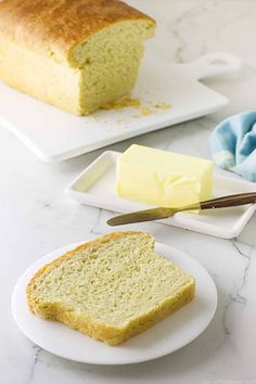 a loaf of bread sitting on top of a white plate next to a piece of butter