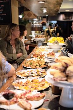 people are sitting at a buffet line with plates of food on the counter and in front of them