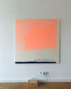 an orange and white painting hanging on the wall next to a plugged in charger