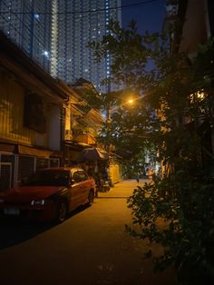 a car parked on the side of a street next to tall buildings at night time