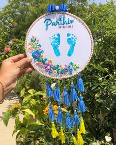 a person holding up a hand and foot print on a sign with tassels hanging from it