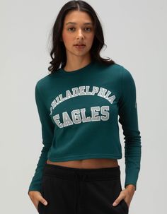 Philadelphia Eagles Long Sleeve Baby Tee. Support Your Team In Style With This Philadelphia Eagles Long Sleeve Baby Tee. With "philadelphia Eagles" Screened Across The Front Chest And A Striking Eagle Graphic On The Left Sleeve, This Fitted Tee Is The Perfect Blend Of Fashion And Fandom. Ideal For Game Day Or Everyday Wear! 94% Cotton, 6% Spandex. Machine Wash. Imported. Model Is Wearing A Size Small. Model Measurements:height: 5'8" Bust: 32"waist: 24"hips: 35" Philadelphia Eagles Shirts Women, Philadelphia Eagles Crop Top, Philadelphia Eagles Sweater, Philadelphia Eagles Womens Shirts, Eagles Sweatshirt, Baby Graphic Tees, Top Graphic Tees, Philadelphia Eagles, Workout Tee