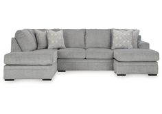 a gray sectional couch with pillows on it's back and the seat facing outward