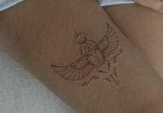 a small tattoo on the thigh of a woman's leg with a bird flying above it