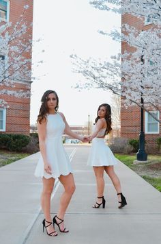 two young women in white dresses holding hands