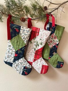 three christmas stockings hanging from a tree branch