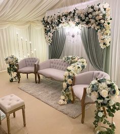 an elegant wedding setup with white flowers and greenery on the wall, couches and chairs