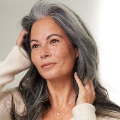 an older woman with gray hair is holding her hand on her head and looking at the camera