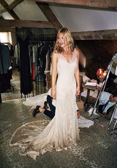 a woman in a white dress standing next to a pile of clothes and other people