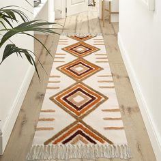 a white and orange rug with tassels on the floor next to a door