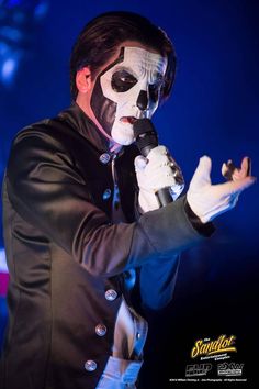 a man with black and white face paint holding a microphone