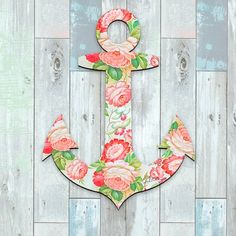 an anchor with flowers painted on it sitting against a wooden wall in front of planks