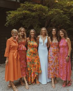 four women in dresses standing next to each other