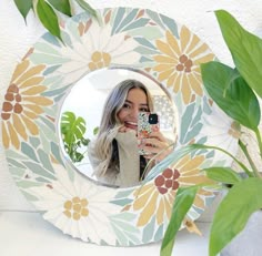 a woman taking a selfie in front of a flowered mirror with her cell phone