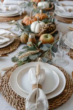 Thanksgiving table setting perfect for small spaces: a close up of a nordic themed table decor for thanksgiving, with woven chargers, white ceramic plates, white linen napkin elegantly folded and a woven napkin ring with one wheat stalk . The centrepiece is: pumpkins and fruits in an charming woven basket, seasonal foliage. Modern Thanksgiving Table Settings, Thanksgiving Table Setting Ideas, Fall Dining Table Decor, Thanksgiving Dinner Table Decorations, Fall Dining Room Table, Simple Thanksgiving Table