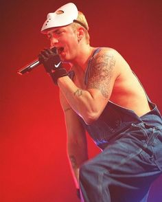 a shirtless man holding a microphone in his right hand and wearing jeans on the other side