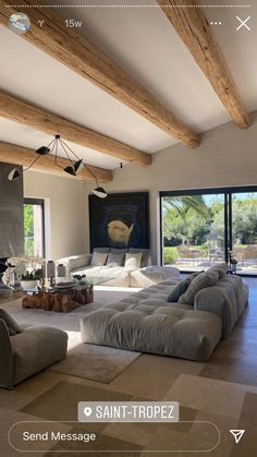 a large living room with lots of furniture and wood beams on the ceiling, along with sliding glass doors leading to an outdoor patio