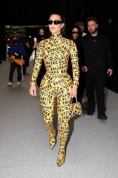 a woman in a yellow and black outfit is seen walking through an airport with other people