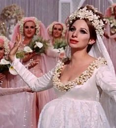 the bridesmaids are dressed in white dresses and flowered headpieces, with one woman holding her hand out