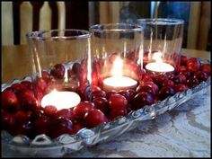 candles are lit in glass bowls filled with cherries