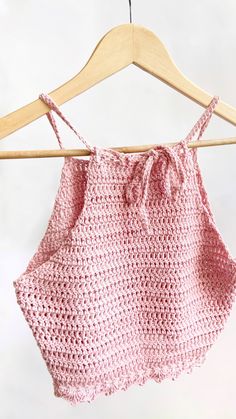 a pink crocheted top hanging on a wooden hanger