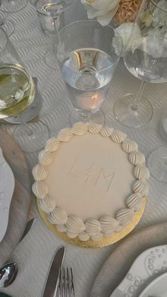 a table set for an event with a cake and wine glasses on the table top