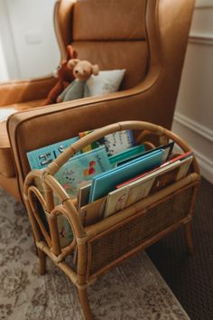 a wicker basket filled with books on top of a carpet next to a chair